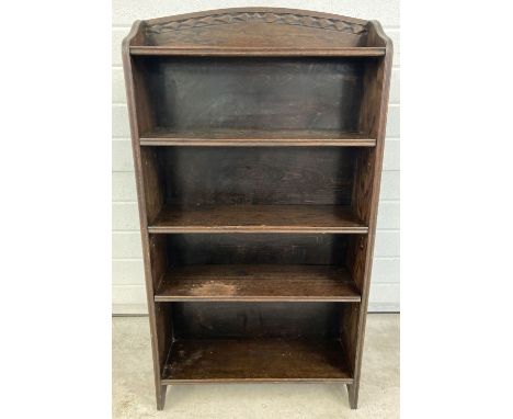 A vintage dark oak bookcase with adjustable shelves and carved detail to shaped top.  Approx. 115 x 61cm.
