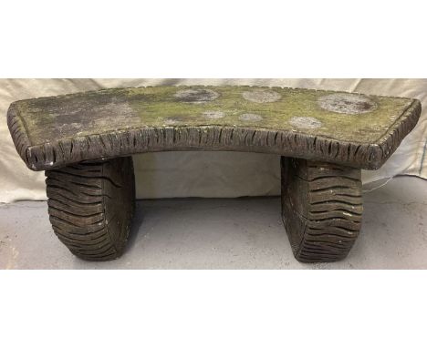 A large vintage painted brown concrete garden bench with log design to seat and supports. Side supports have oak leaf decorat