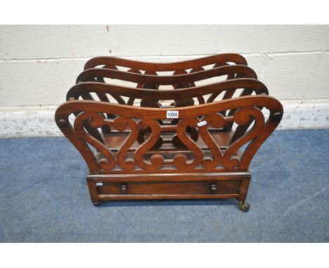 AN EARLY 20TH CENTURY MAHOGANY CANTERBURY, with scrolled details, and a single drawer to one side, raised on ceramic castors,