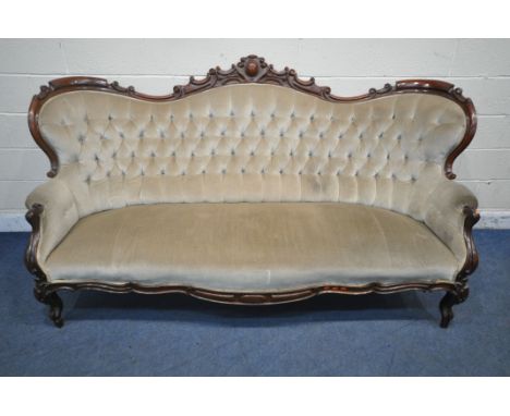 A VICTORIAN MAHOGANY FRAMED SOFA, the decorative frame with foliate scrolls, crest to top centre, buttoned backrest, padded a