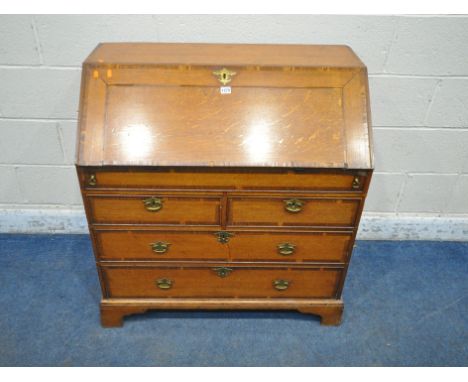 A GEORGIAN OAK BUREAU, the fall front door enclosing a fitted interior, above two short and two short drawers, raised on brac