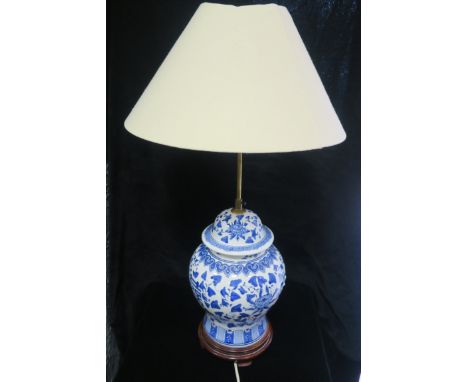 A BLUE AND WHITE TABLE LAMP, of baluster form with shade raised on a cherry wood stand,73cms high.