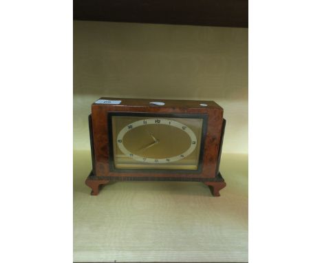 A 20th CENTURY ART DECO STYLE BURR WALNUT VENEERED MANTLE CLOCK of rectangular form with ebony banding on scrolled supports 