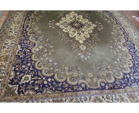 A WOOL RUG, the light green beige and mauve ground with central floral panel within a conforming border,400cms x 305cms.