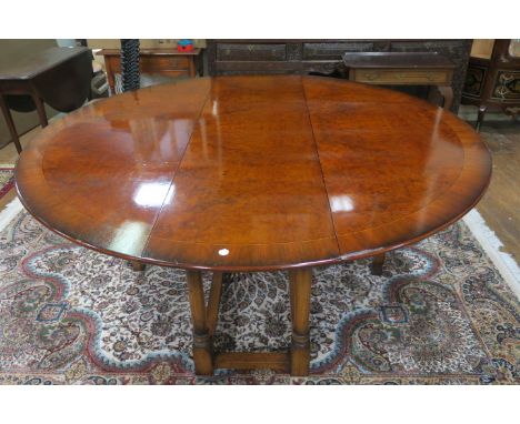 A GEORGIAN STYLE BURR WALNUT VENEERED CIRCULAR DINING ROOM TABLE, the cross banded top with satinwood string inlay above a tu