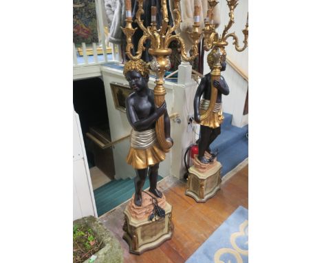 A FINE PAIR OF BLACKAMOOR FIGURES, each shown standing holding a six branch candelabra aloft raised on a naturalistic base an