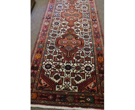 A PERSIAN HAMADAN RUNNER, the light pink and beige ground with central panels with palmes and hooks within a conforming borde