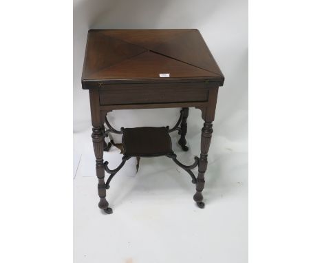 AN EDWARDIAN MAHOGANY ENVELOPE GAMES TABLE the rectangular hinged top opening to reveal a green baize interior with sunken co