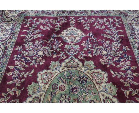 A RUG, the wine and light green ground with central floor panel within a performing border. 142cms x 212cms