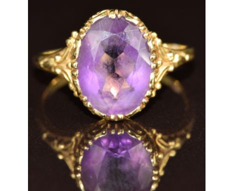 An 18ct gold ring set with an oval cut amethyst, with embellished shoulders, 3.9g, size N