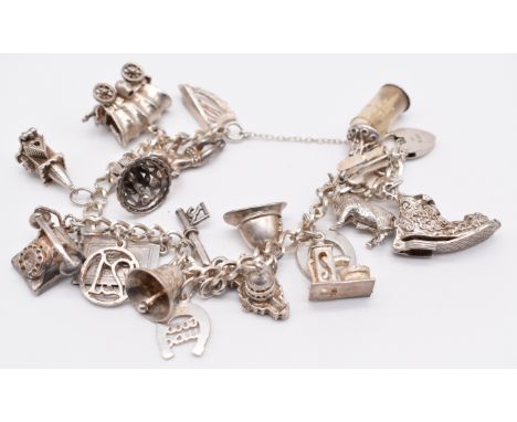 A silver charm bracelet with nineteen silver charms including 'good luck' horseshoe, cherub, church, harp, driving license, e