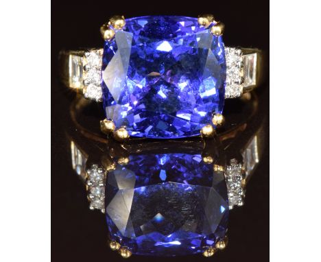 An 18ct gold ring set with a cushion cut tanzanite of approximately 7.85ct with round and baguette cut diamonds to the should