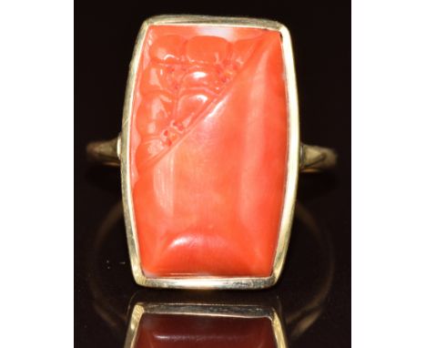 A 9ct gold ring set with a partly carved coral cabochon, 6.3g, size R