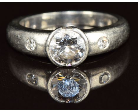 A platinum ring set with a round cut diamond of approximately 1.1ct and two smaller diamonds, 10.4g, size O