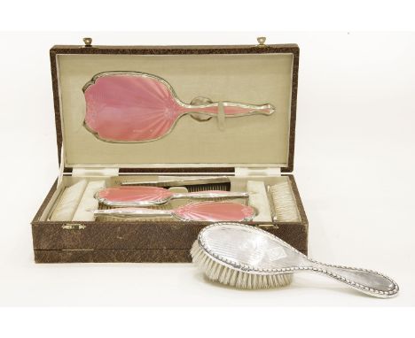 A cased Art Deco silver and pink guilloché vanity dress set,comprising: a hand mirror, two hairbrushes, two clothes brushes a