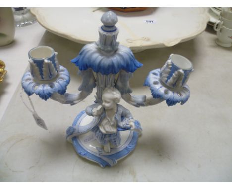 A Meissen porcelain twin branch figural candlestick; moulded with a boy leaning; bearing blue cross sword marks to base