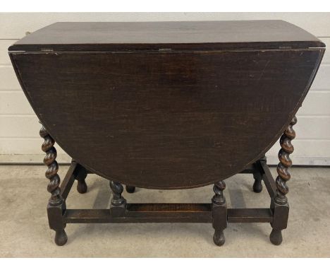 A Victorian dark oak barley twist drop leaf, gate leg dining table. With oval shaped top and bun feet. Approx. 73cm tall x 91