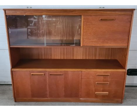 A mid century teak low display unit with glass sliding doors, cupboards and 3 drawers. With integral wooden handles, baize li
