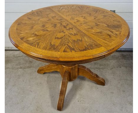 A vintage circular light wood dining table with central turned pedestal base. 4 feet with channelled detail, approx. 76cm tal