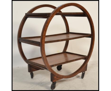 A 1930's Art Deco teak trolley of circular form with multiple tiers having faux coromandel tier edges. All raised on original