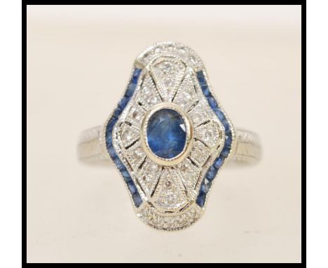 A 1920's 18ct white gold art deco panel ring set with a central oval cut sapphire&nbsp;in a shaped diamond set pierced surrou