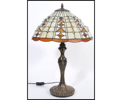 A 20th Century twin bulb Tiffany inspired table lamp, the cast base of Art Nouveau taste having a bronzed effect finish, surm