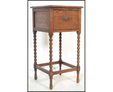 An early 20th Century Edwardian oak tall oak pot cupboard, the flared top with fall front flap underneath raised on bobbin tu