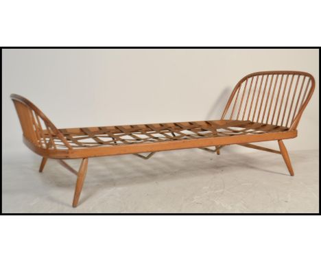 A mid century Ercol blonde beech and elm wood single bed / studio day bed / sofa settee. Raised on shaped legs with show wood