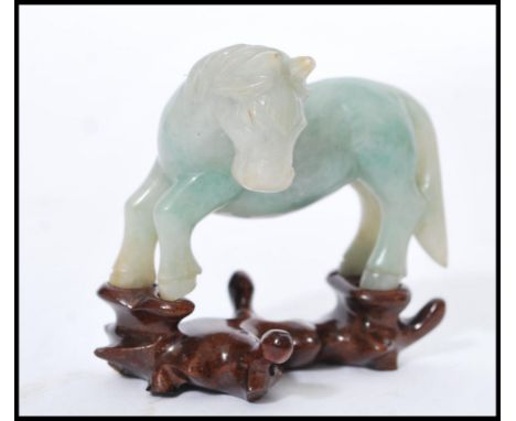 A vintage 20th century Chinese carved green jade figurine of a horse raised on carved wooden socle base. 18cm high.&nbsp;
