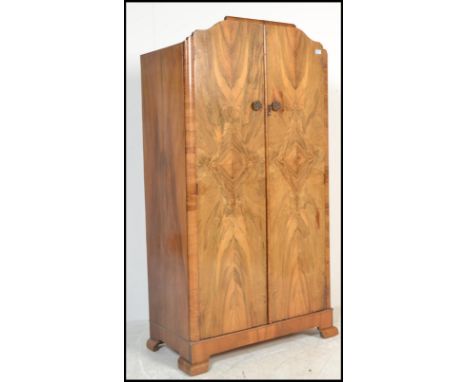 A 1930's Art Deco walnut wardrobe. Shaped feet with twin full length panel doors enclosing a sectional interior set within.&n