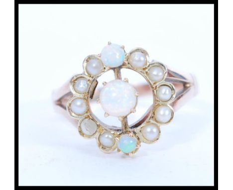 An early 20th Century 9ct gold ring set with a round opal with two smaller accent opals and a halo of seed pearls. Total weig