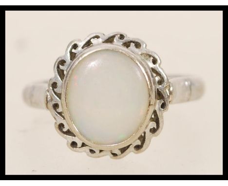 A 14ct white gold opal ring having a central opal panel in scrolled mount. Stamped 14k and tests as such. Weighs 3 grams size