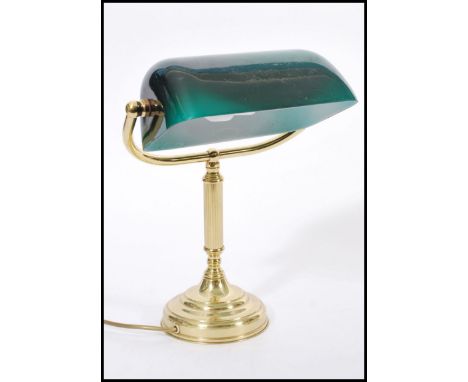 A 20th century brass bankers lamp raised on circular base with adjustable green glass shade. 36cm high.&nbsp;