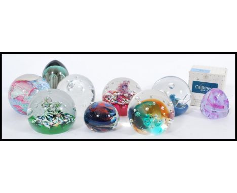 A collection of nine 20th century glass paperweights, the paperweights predominately by Caithness, all the paperweights of di