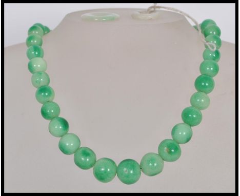 A vintage Chinese green jade prayer bead necklace having a graduating set of round beads and barrel clasp along with two carv