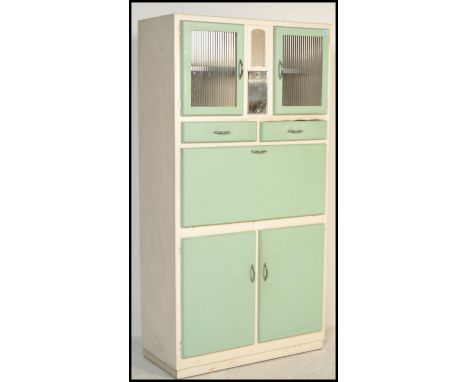 A vintage retro mid 20th Century all in one kitchen larder cupboard having pistachio / mint green painted doors on a white ca