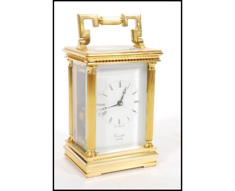 A 20th century modern Comitti of London brass cased carriage clock with Roman numeral chapter ring, open escapement window wi