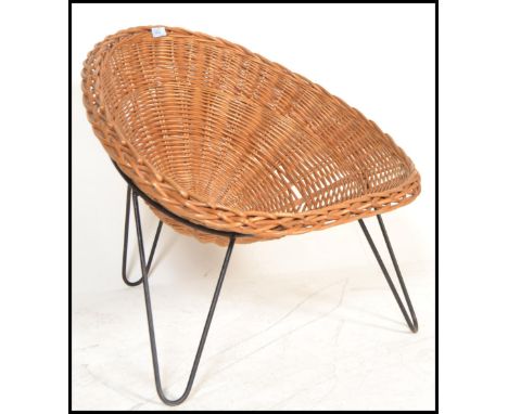An original retro 20th century wicker tropics chair / armchair raised on a tripod hairpin leg structure constructed from a si