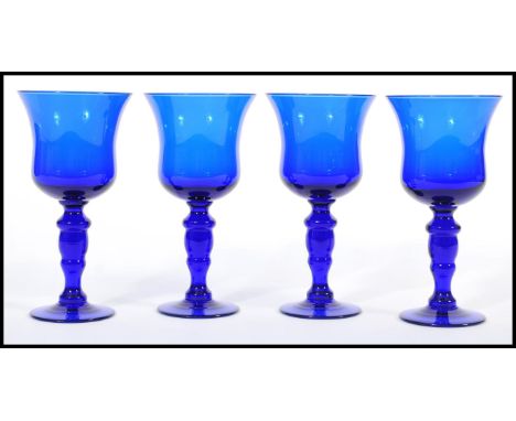 A set of four unsigned Bristol Blue glass goblet wine glasses raised on circular bases with baluster stems and bell bowl atop