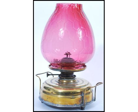 A 19th Century Victorian oil lamp having a large round brass base with handles to either side raised on round feet having a l