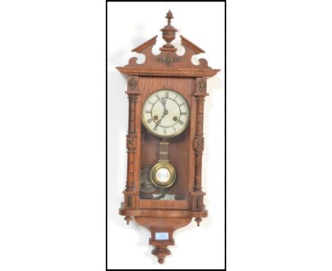 A Vienna-styled wall clock, oak case with opening glazed door flanked by turned decoration, surmounted by an architectural st