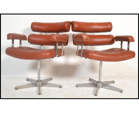 A pair of retro 20th century salon / barbers. Having a red button back vinyl upholstery, reclining back pads and arm rests be