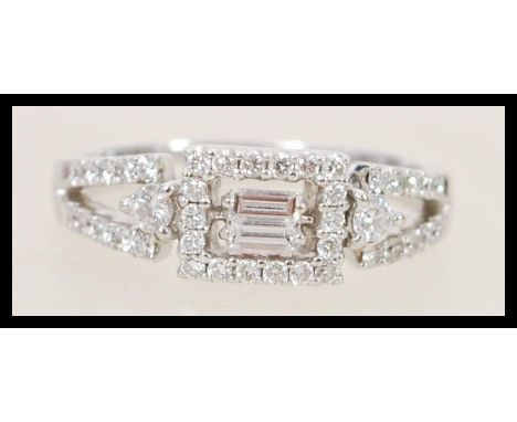 A Mappin and Webb 18ct white gold and diamond art deco style ring set with a central rectangular diamond having pierced geome