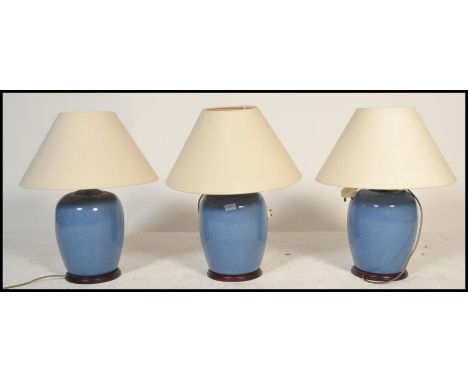 A set of 3 contemporary large ceramic blue glaze bulbous table lamps - lights. Each raised on wooden socle plinths having goo