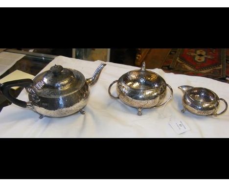 A near matching three piece Arts &amp; Crafts style hammered silver teaset - the cream jug and sugar bowl with Birmingham hal