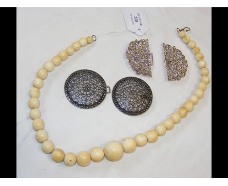 An ivory necklace, together with silver buckles 