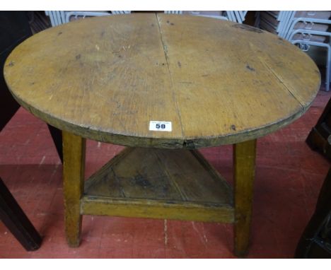 AN ANTIQUE PINE CRICKET TABLE, the 70 cms diameter top on a standard peg-jointed frame with undertier shelf, 71.5 cms high