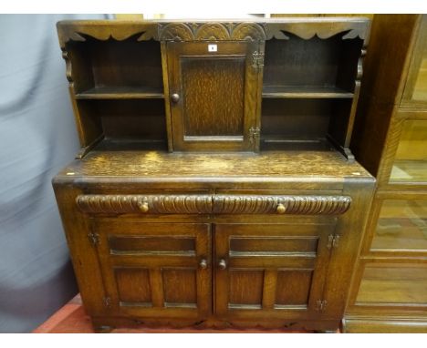 A CIRCA 1930's CARVED OAK SIDEBOARD with shelf and central cupboard door top, twin frieze drawers and lower cupboard doors, o