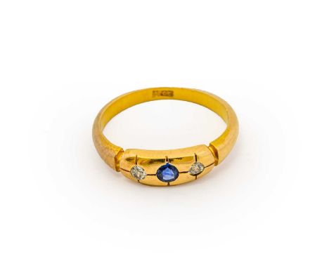 A sapphire and diamond three stone ring, a round cut sapphire flanked by old cut diamonds, inset within a yellow plain polish