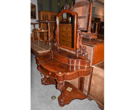 An impressive Victorian carved mahogany dressing table, the mirror with shelf surmount, held by tapering fluted uprights and 